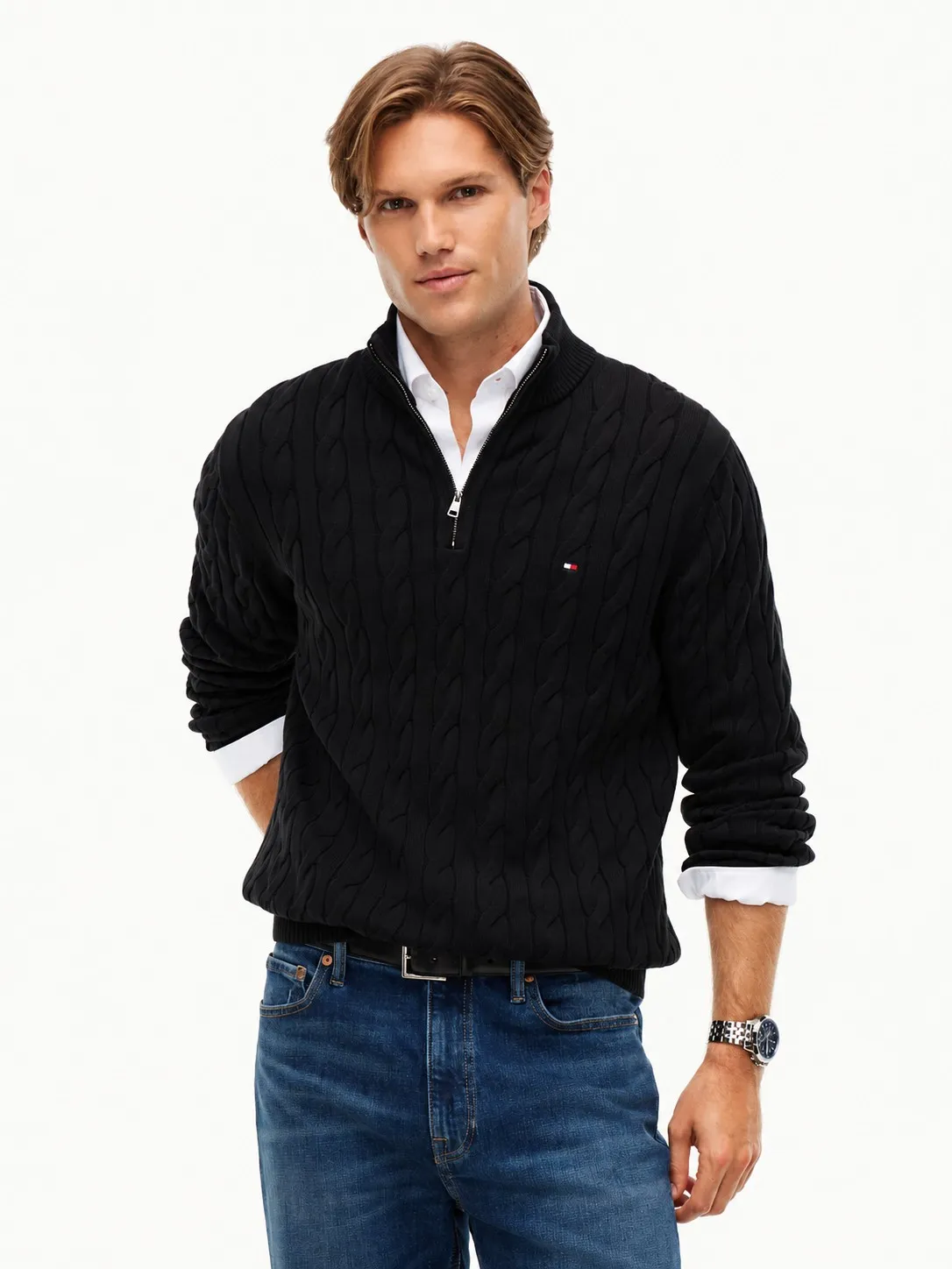 Buzo Tommy Hilfiger negro puesto, plano medio de un modelo que lo lleva con camisa blanca debajo y jean azul